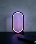 Capsule Lamp lit violet on a dark desk