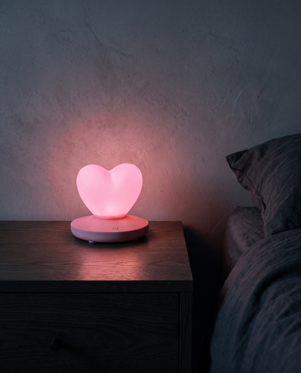 Heart Lamp glowing pink on a bedside table