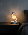 Orbit Lamp glowing warm white on a bedside table at night