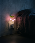 Mushroom Night Light glowing pink in a bedroom wall outlet