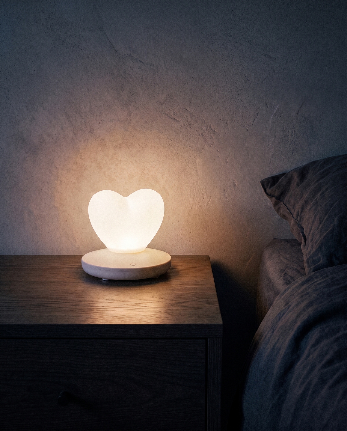 Heart Lamp in white, glowing on a bedside table