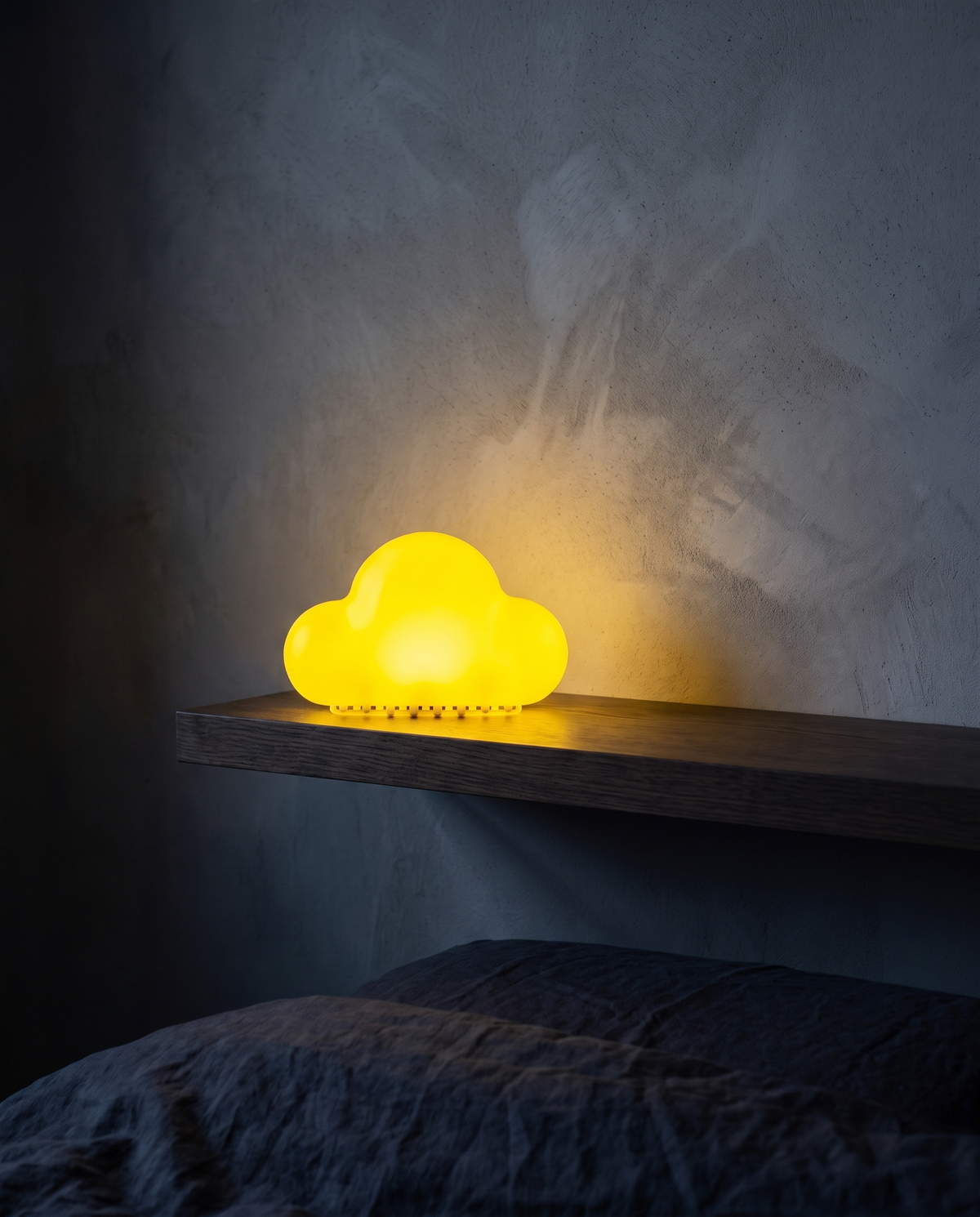 Cloud Light in yellow, glowing on a floating shelf above a bed