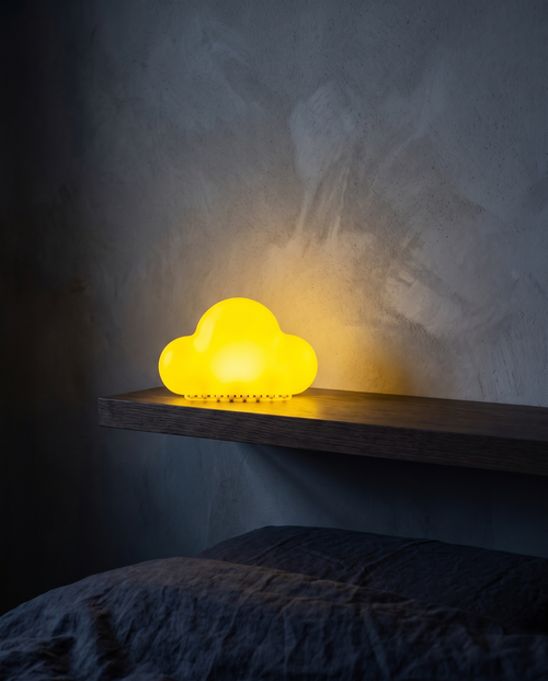 Cloud Light in yellow, glowing on a floating shelf above a bed
